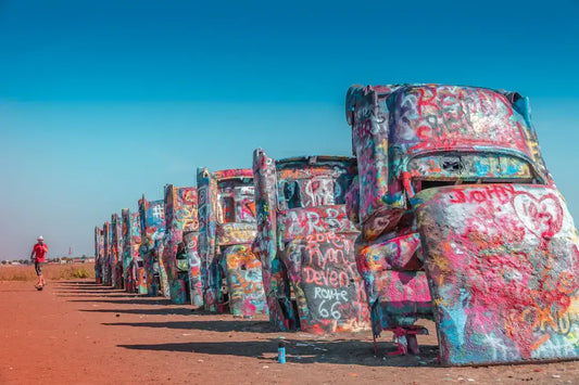 Colorful, graffiti-covered cars at Cadillac Ranch under a clear blue sky, perfect inspiration for car-themed tee art.