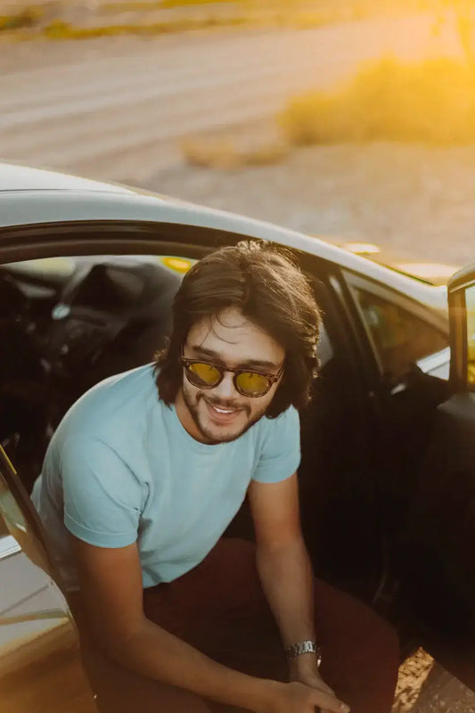 Man with sunglasses enjoying car culture and the open road during sunset.