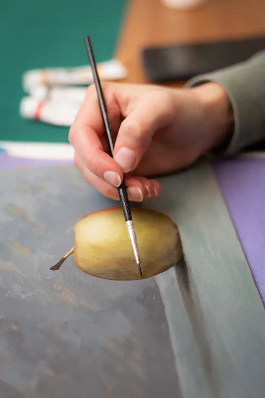Artist painting realistic apple slice on canvas, blending art and creativity