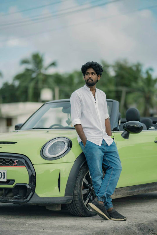 Stylish man leaning against a green convertible, showcasing the blend of car culture and fashion trends.
