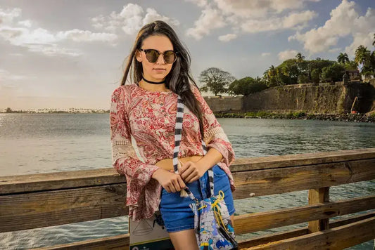 Fashionable woman in sunglasses on San Juan pier, showcasing Puerto Rican vibes in a vibrant outfit.