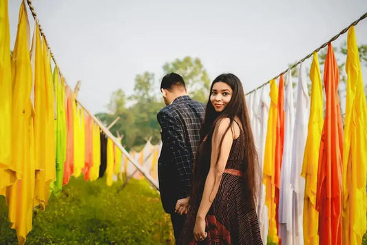 Couple holding hands in a vibrant outdoor setting with colorful fabrics, capturing a romantic moment perfect for Valentine's Day.