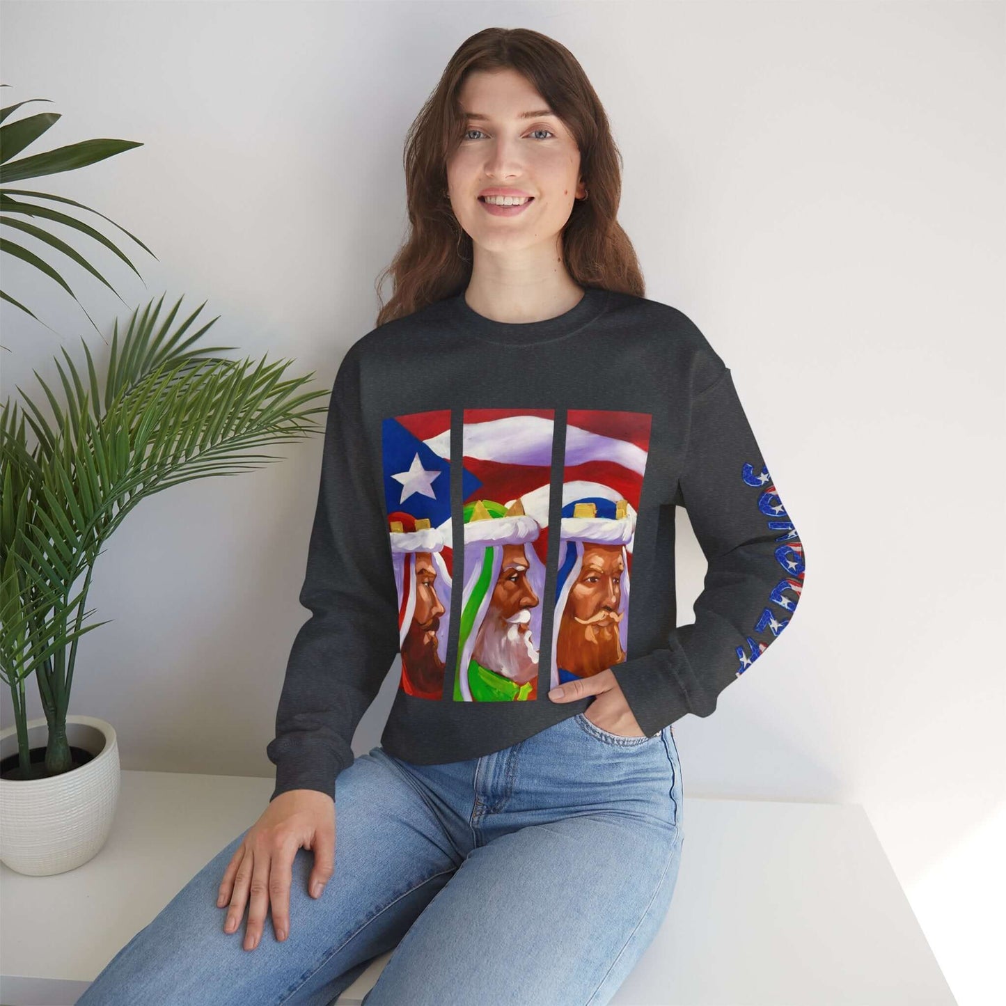 Person wearing a festive black holiday sweater featuring Three Kings design with Puerto Rican flag sky background, sitting indoors.