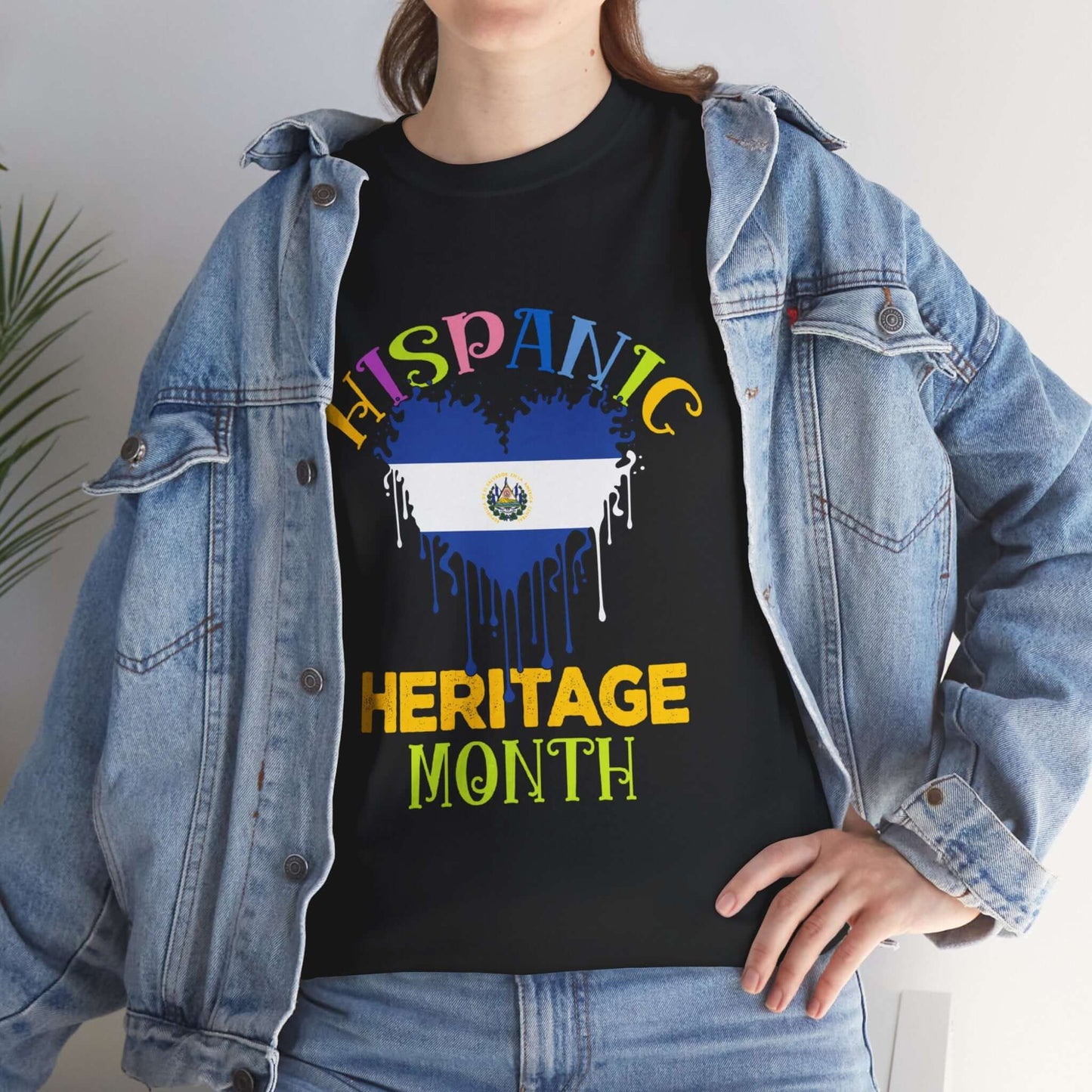 Woman wearing Hispanic Heritage Month Salvadorian Heart Flag Graphic Tee with colorful text and denim jacket