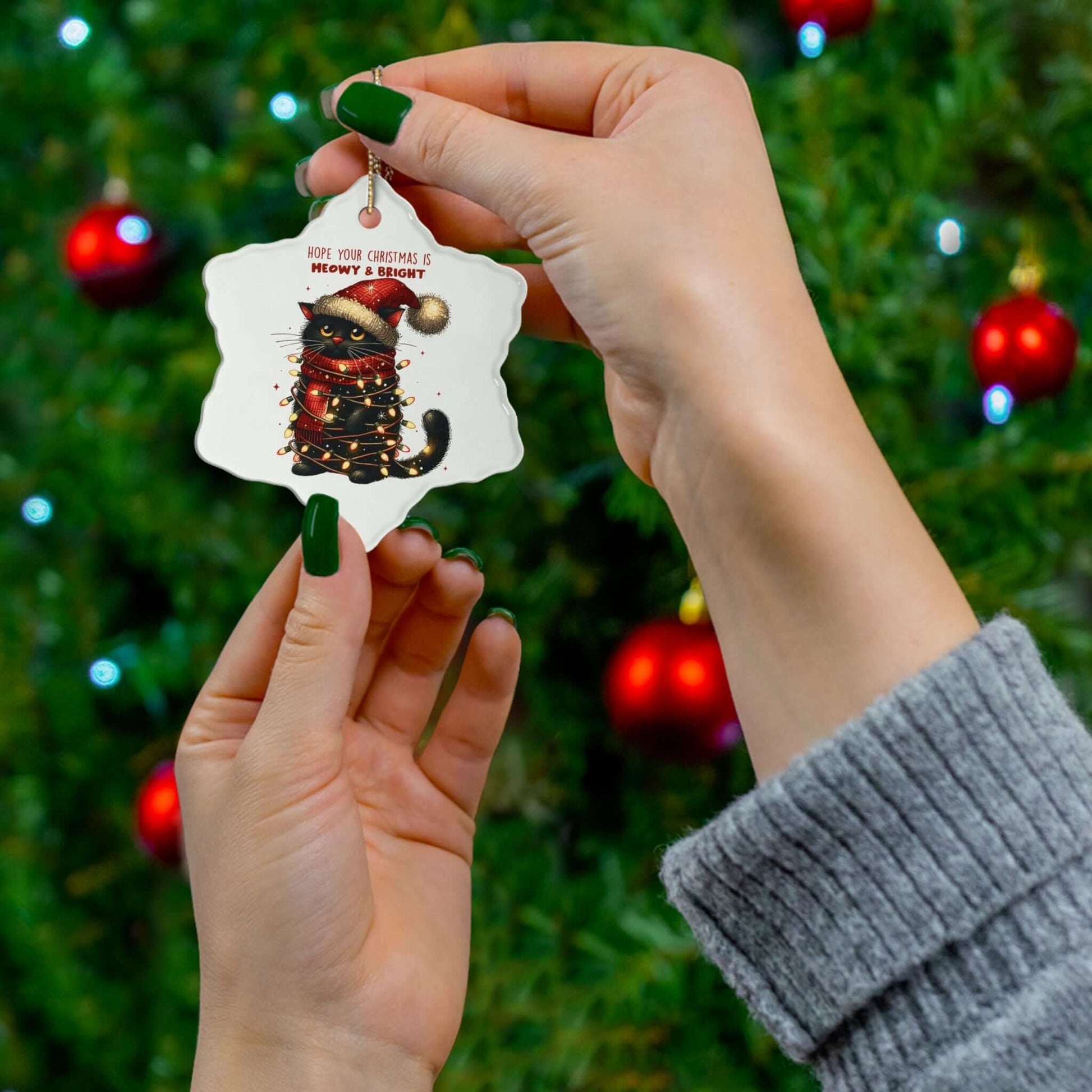 Hand holding a Meowy Xmas ceramic ornament in a festive setting, perfect for cat lovers and holiday decor.