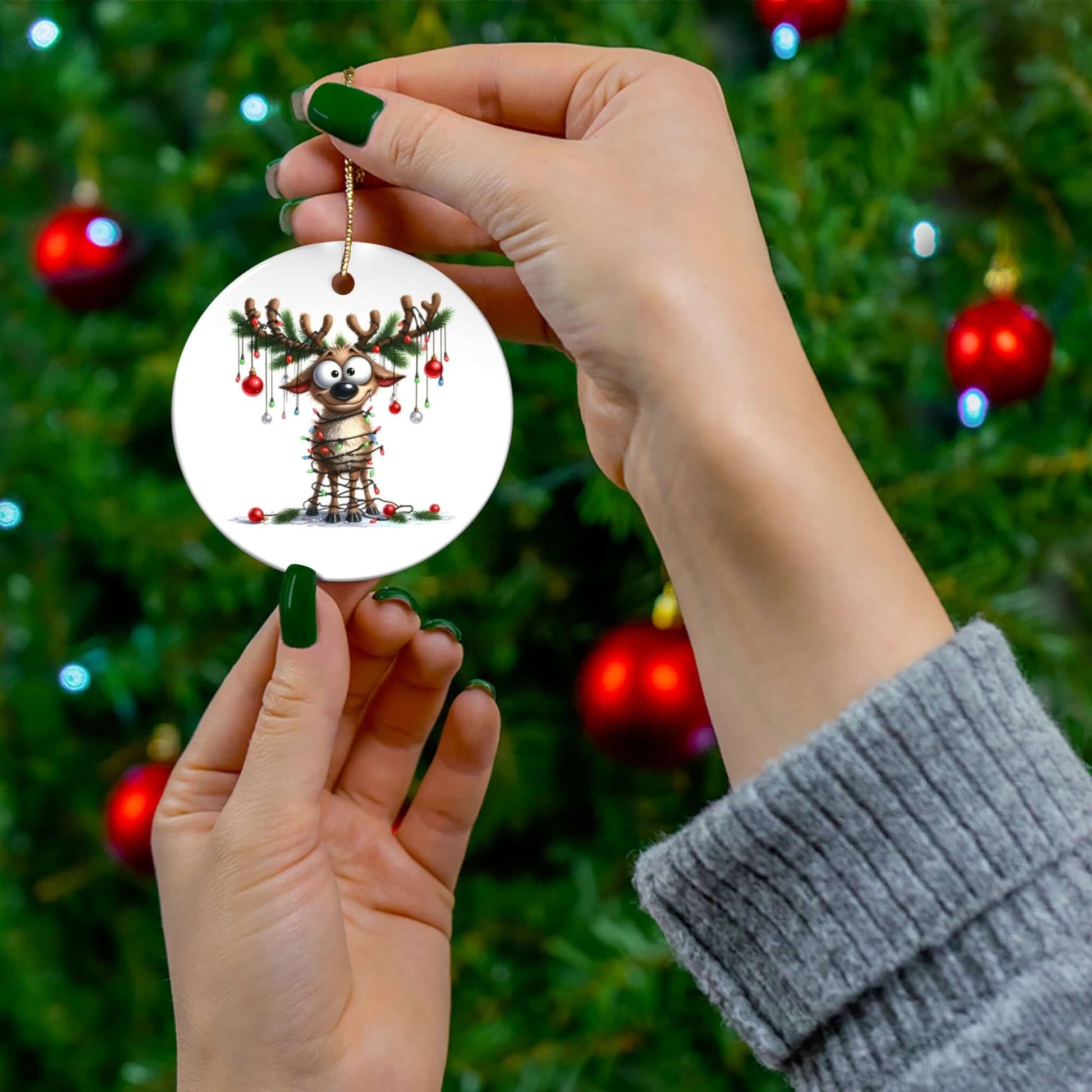 Hand holding a ceramic ornament featuring a funny reindeer wrapped in Christmas lights, perfect for festive decor.