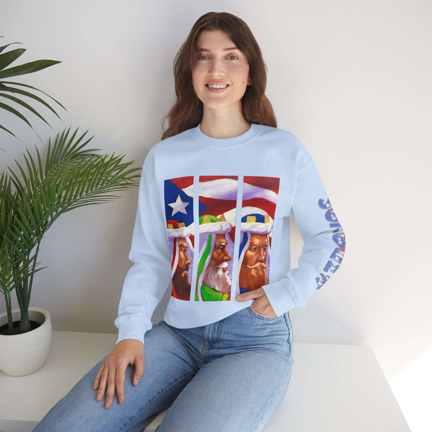 Woman wearing Three Kings Holiday Sweater with Puerto Rican flag design, seated indoors next to a plant.